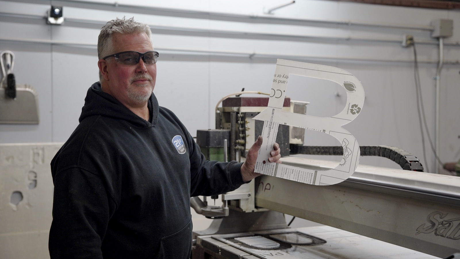 Fabricator operating CNC router to cut sign letters