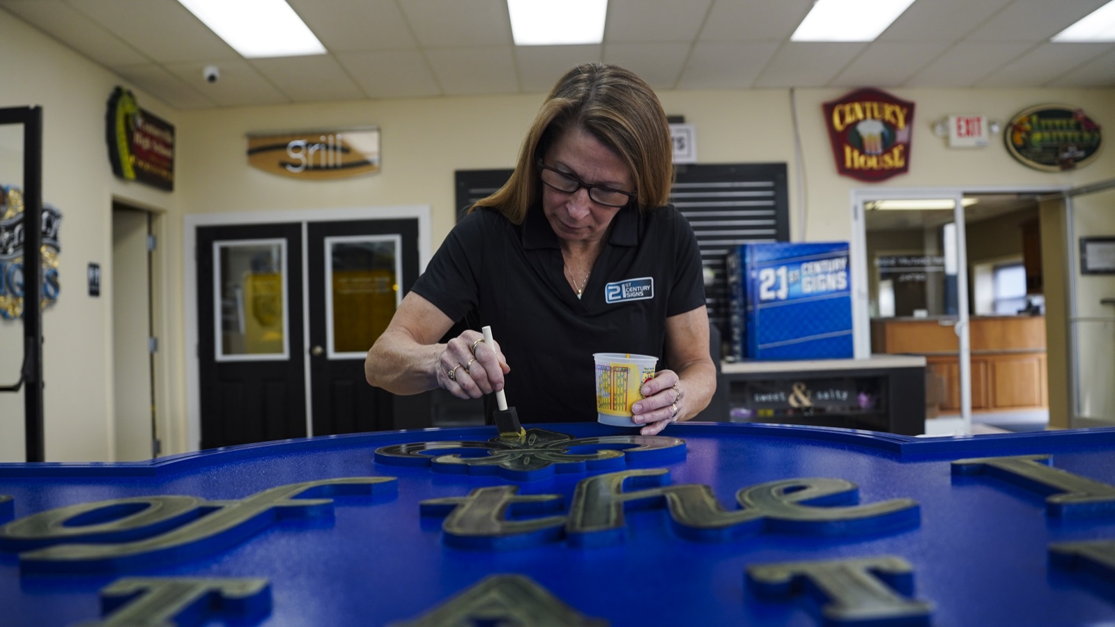 Artisan applying gold leaf to a dimensional sign