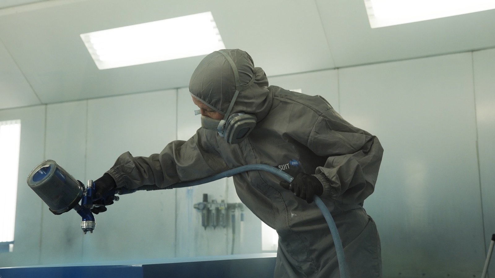 Worker spray painting large sign panels in the paint booth