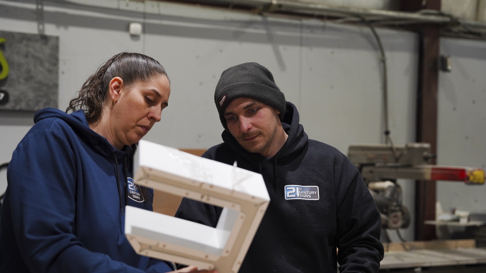Team members inspecting a fabricated channel letter before shipping