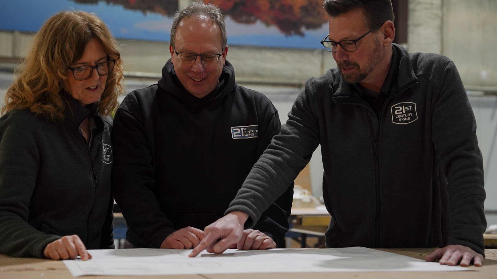 Three team members reviewing project plans together in the workshop